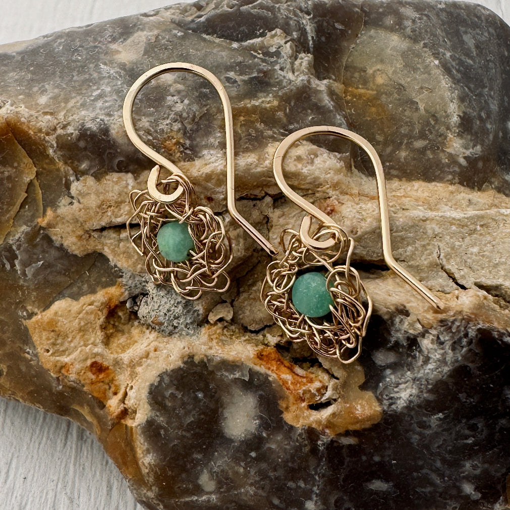 Gold earrings with turquoise stones on a stone surface