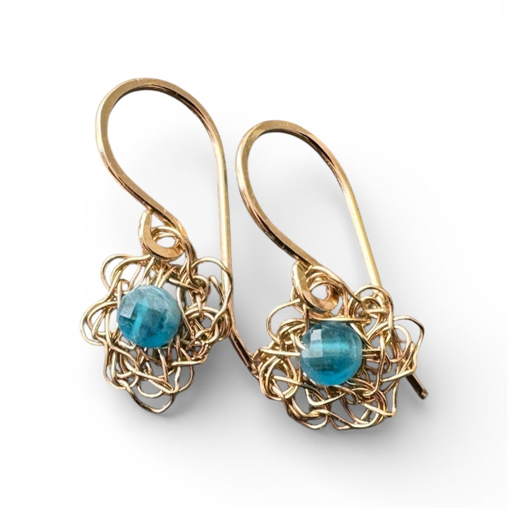 Gold wire-wrapped earrings with blue gemstones on a white background