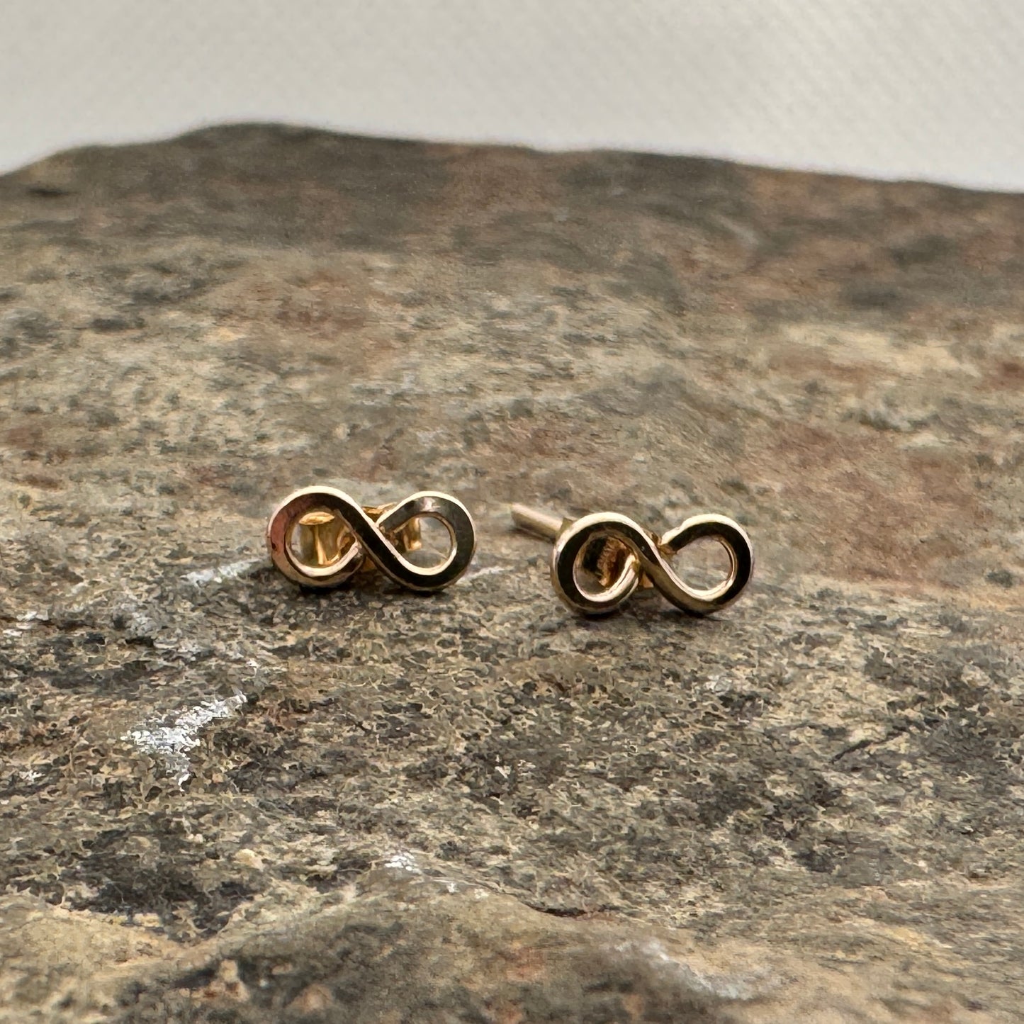Gold filled infinity studs by Izabela Rocks on the rock surface