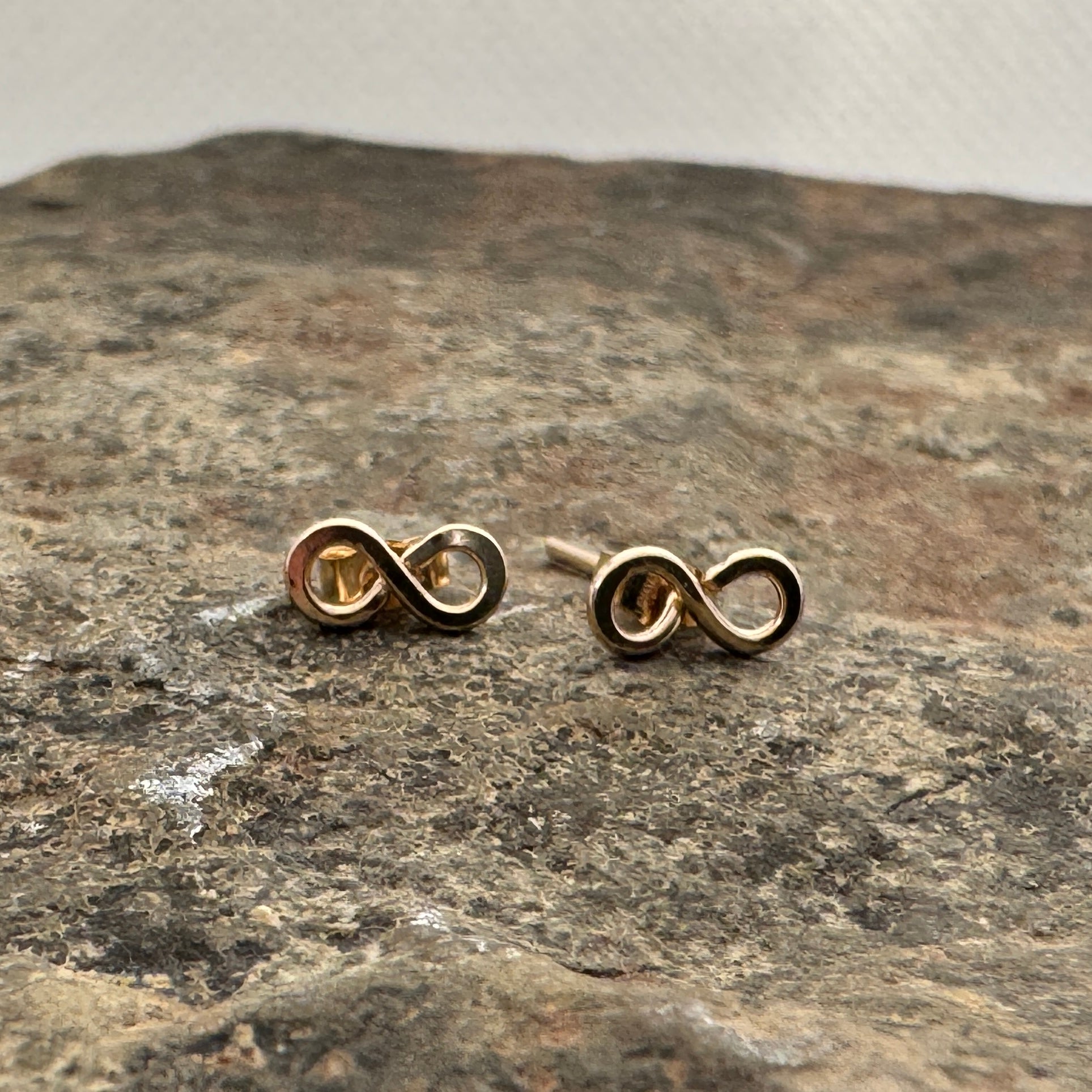 Gold filled infinity studs by Izabela Rocks on the rock surface