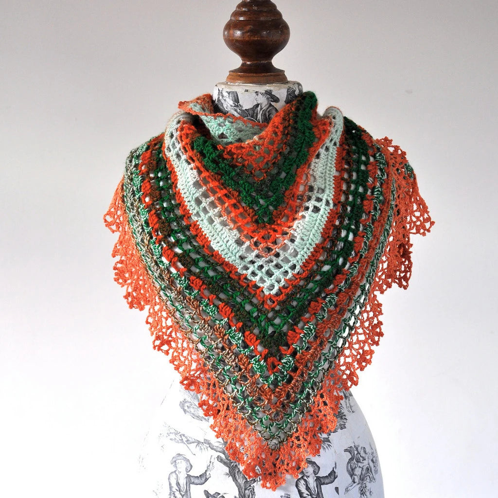 Colorful crocheted shawl on a mannequin against a white background