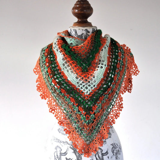 Colorful crocheted shawl on a mannequin against a white background