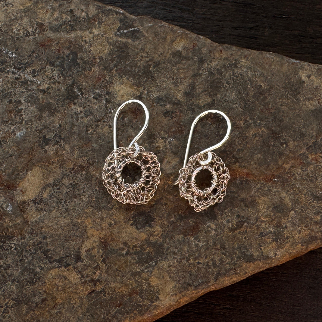 Silver wire-wrapped earrings on a wooden surface