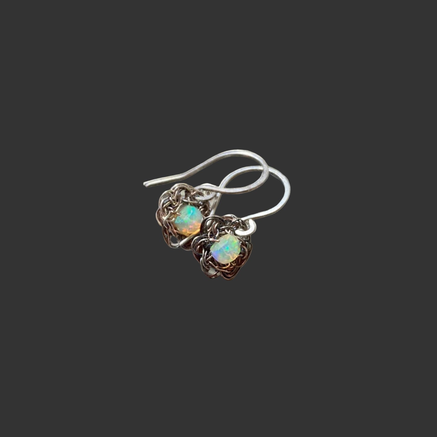 A pair of silver crocheted earrings with opal beads.